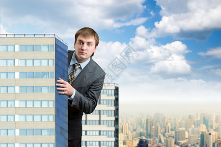 商人站在摩天大楼后面对抗蓝天图片