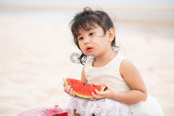 可爱的孩子在海滩上吃西瓜图片