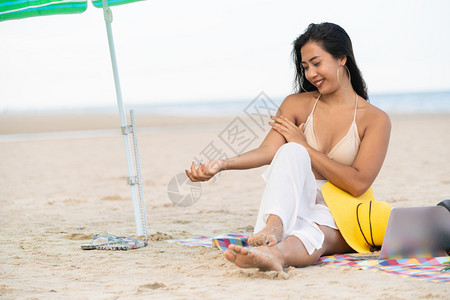 夏天坐在热带沙滩上的年轻女子图片