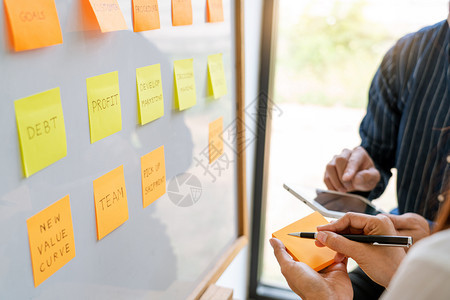 张贴粘笔记纸的年轻商业工人提醒同事在现代工作空间搭接同事时的创造集思广益图片
