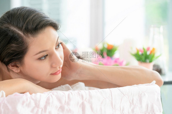躺在温泉水疗床上的放松年轻女子图片