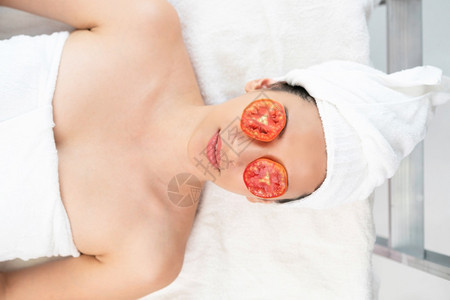放松的年轻女子在豪华温泉度假村接受西红柿的眼部自然治疗图片