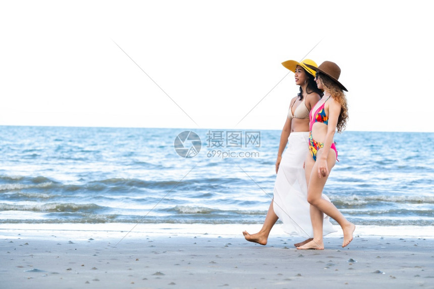 快乐的比基尼妇女一起在暑假的热带沙滩上晒太阳图片