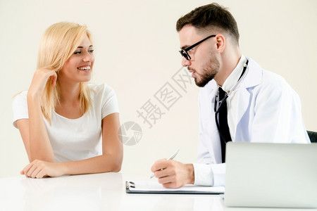 男医生与女病人交谈同时在桌子上记录图片