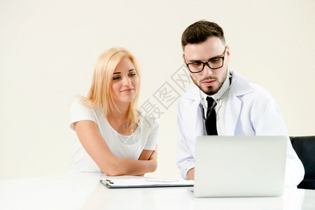 男医生与女病人交谈同时查看桌上病人健康数据图片