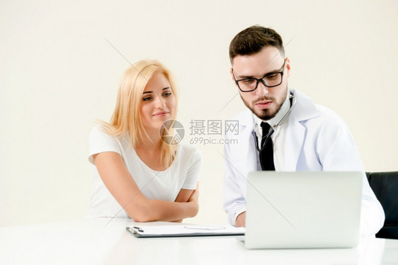 男医生与女病人交谈同时查看桌上病人健康数据图片