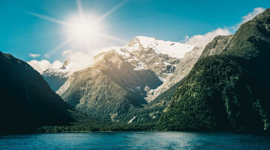 以及湖面和山地景观夏季阳光下雪峰以蓝色天空背景在密尔福德音响菲奥兰公园南新西兰岛拍摄图片