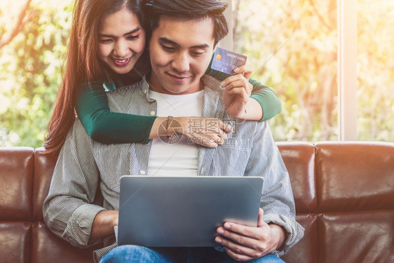 年轻夫妻开心的使用信用卡在家中网购图片