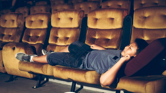 男孩躺在扶手椅上享受看电影图片