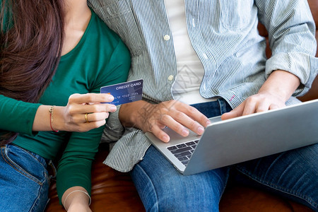 年轻夫妇使用信用卡在家中的互联网站上在线购物概念图片
