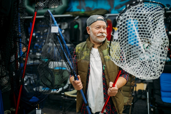 在渔场鱼钩网上选择的快乐渔夫在背景上选择网钓鱼和打猎的设备工具在商店的展品上附属选择鱼饵组合在渔场上选择网的快乐渔夫在场上选择网图片