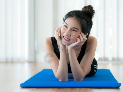 快乐的年轻女子趴在瑜伽垫上图片