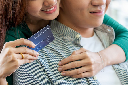 年轻夫妇使用信卡在家中的互联网站上在线购物信用卡号码是假冒的信用卡上没有个人信息网上商业购物概念图片