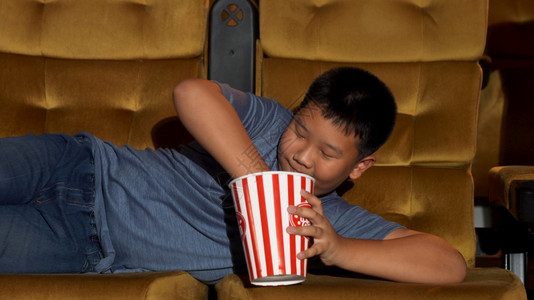 男孩躺着看电影开心地吃爆米花图片