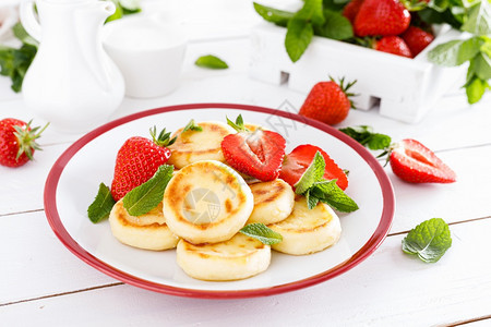 奶酪煎饼薄或配新鲜草莓和酸奶的复尼基饼薄煎或健康和美味的早餐图片