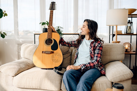 家里有吉他带耳机吉他乐器房间里放松女音乐情人休息带耳机的可爱女人图片