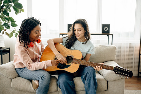 女人在家里学弹吉他漂亮的女友在房间里听耳机放松声音情人睡在沙发上女朋友一起闲暇图片