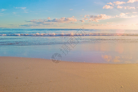 海滩景色不错日出时波浪温和到达沙滩海日出场景图片