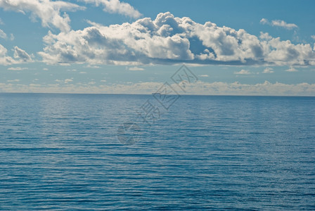 一艘远在平坦而静的深蓝热带海洋上的船图片