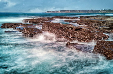 海岸上撞岩石的强烈海浪背景图片