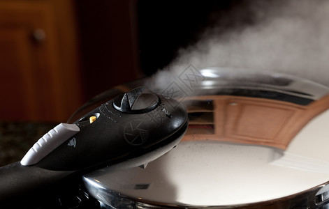 蒸摆脱压力炊具盖与现代厨房的反射背景图片