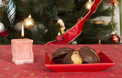 圣诞糖果和蜡烛在圣诞树前面的桌子上图片