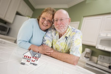 快乐的成年夫妇在厨房柜台看小模范家图片