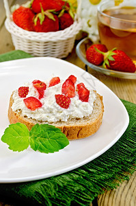一片法式面包夹着咖喱奶油草莓和薄荷盘子餐巾纸篮浆果玻璃杯木板茶图片