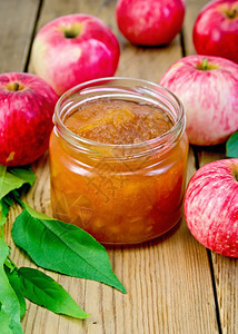 玻璃罐里的苹果酱新鲜红苹和木板上的叶子图片
