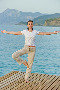 女孩站在码头的一条腿上保持平衡图片