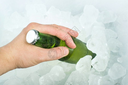手握着啤酒和冰块的瓶子图片