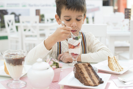孩子吃草莓冰淇淋巧克力蛋糕放在桌上图片