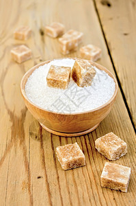 木桌碗中的棕色糖和白立方块图片