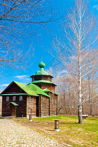 配有绿色屋顶和树枝的木制正教堂图片