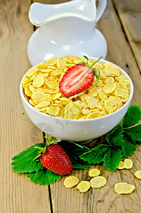 草莓罐头白碗中的玉米片叶子和草莓木板背景的罐头中牛奶背景