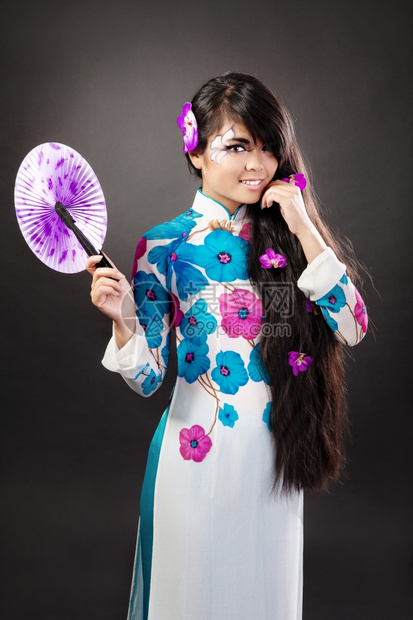 美丽的亚洲女穿着国服拿风扇孤立在黑背上图片