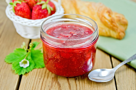 玻璃罐中草莓果酱层包篮子中草莓果餐巾木板上勺子图片