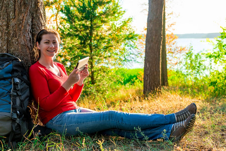 身穿红色t恤的女孩靠着大树图片素材