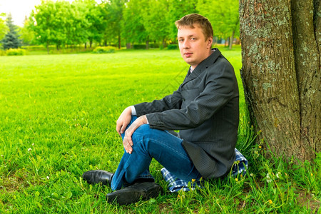 坐在树旁穿西装的男人图片