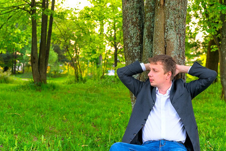 年轻人在一棵高树旁休息图片