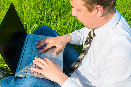 办公室工作人员用笔记本电脑在草坪上工作图片
