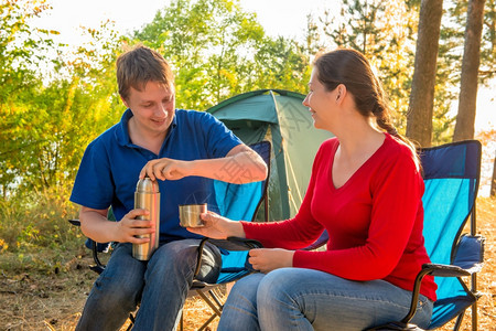 家人在松树附近的帐篷旁边喝茶图片