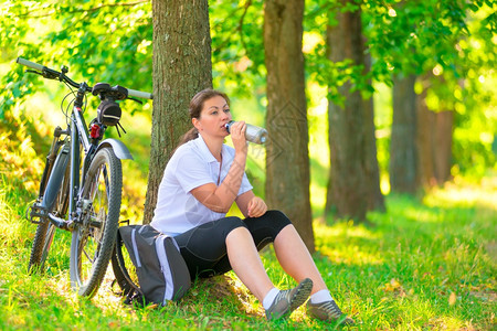 户外骑行自行车的年轻女孩在喝水休息图片