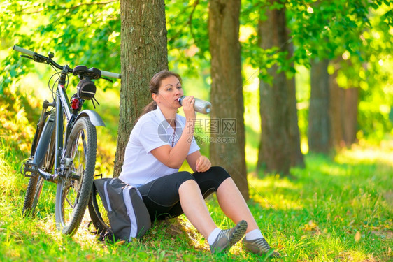 户外骑行自行车的年轻女孩在喝水休息图片