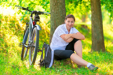 年轻女人坐在自行车前休息图片