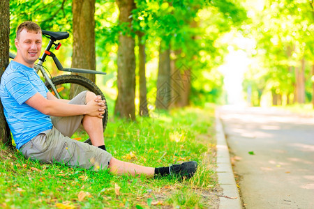 年轻男人坐在自行车前休息图片
