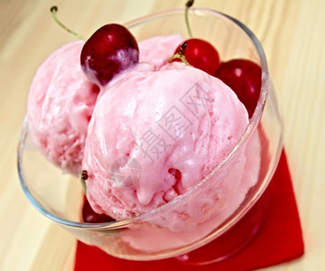 红纸巾上的樱桃冰淇淋放在玻璃碗里红纸巾上的樱桃冰淇淋放在木板的背景上图片