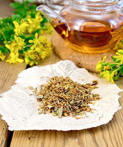 一块纸上多汁的干枯花朵茶壶中的叶和木板背景上的鲜花塔桑图片