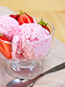 草莓冰淇淋在玻璃碗里加草莓勺子放在木板上的餐巾纸图片
