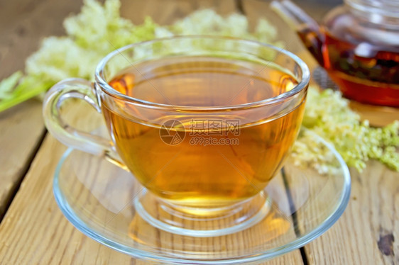 一杯茶壶和里的草地甜鲜的草地甜花放在木板上图片